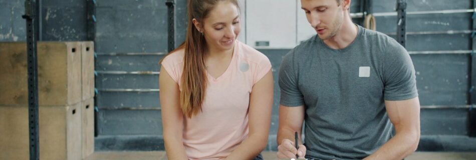 Trainer and client discussing workout plan in gym