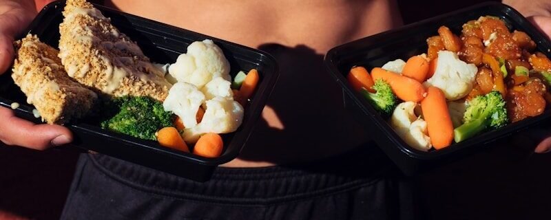 topless man in black shorts holding cooked food