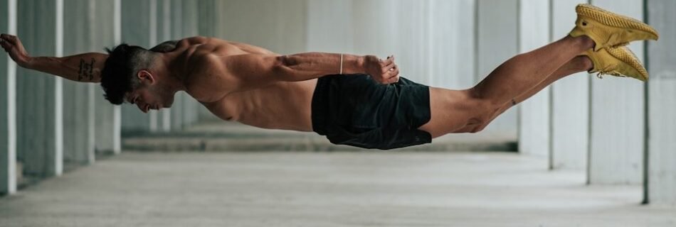 a shirtless man is diving in a parking garage