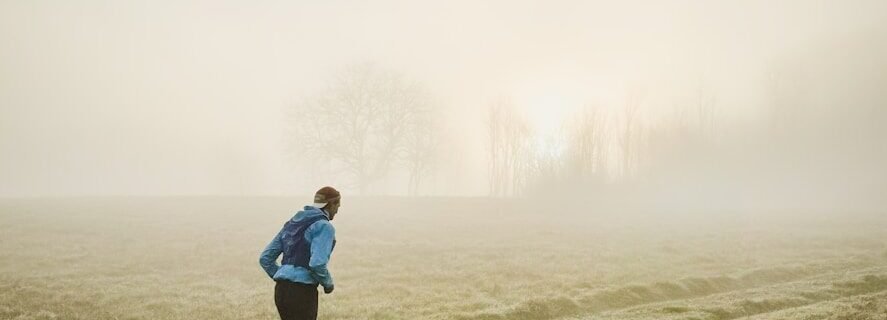 Man running through a misty field at sunrise