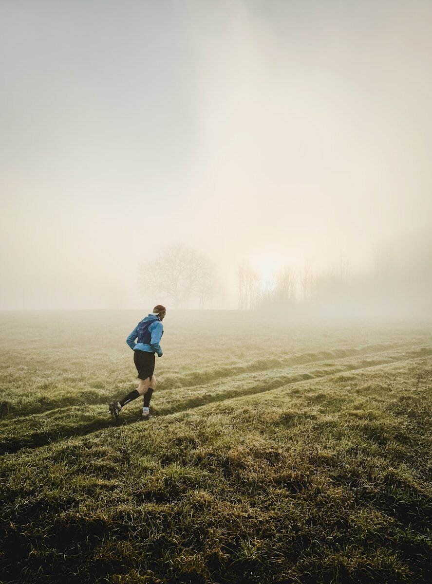 Man running through a misty field at sunrise