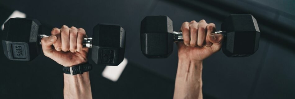 a man lifting two dumbs in a gym